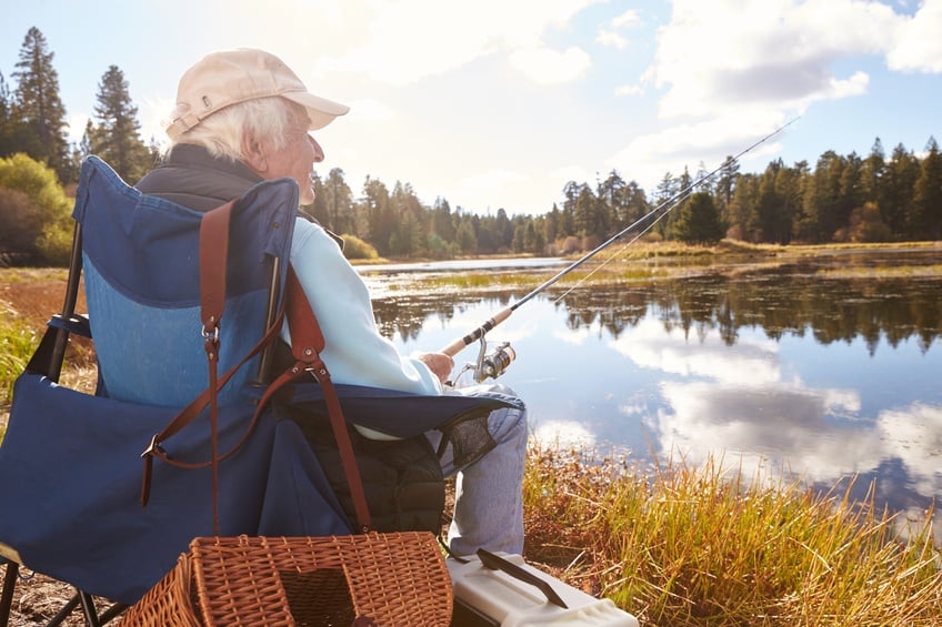Senior man sits fishing in a lake