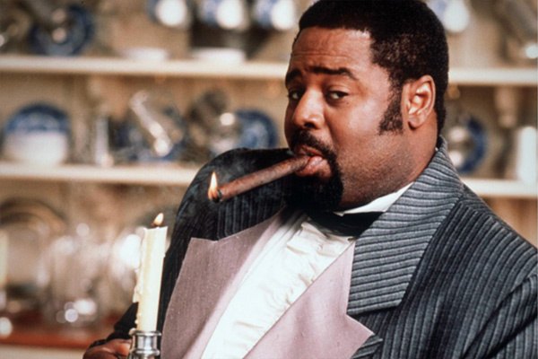 Chi McBride smokes a cigar and holds a candle in a scene from The Secret Diary of Desmond Pfeiffer