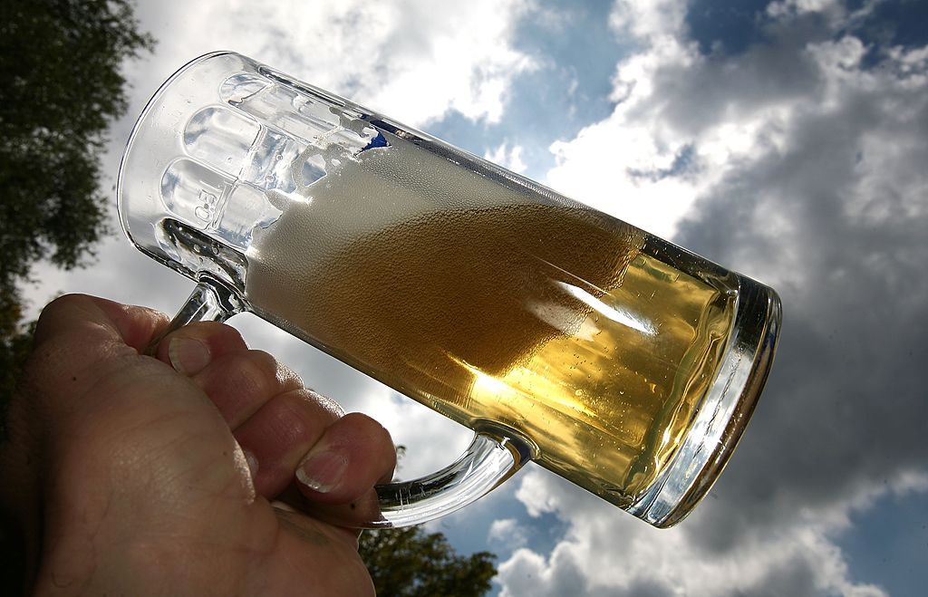 A customer lifts a mug of beer against the sky