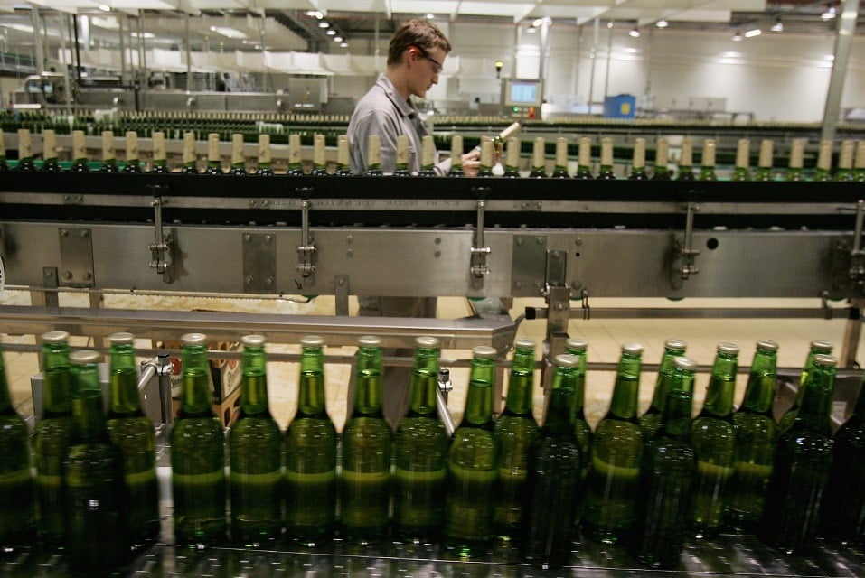 A technician checks a bottle as other bottles of freshly brewed Pilsner-Urquell lager beer run through the bottling plant at the Prazdroj brewery