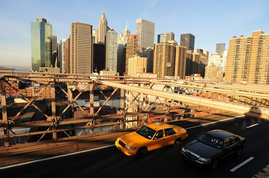 Taxi and a Limousine driving along the Brooklyn bridge