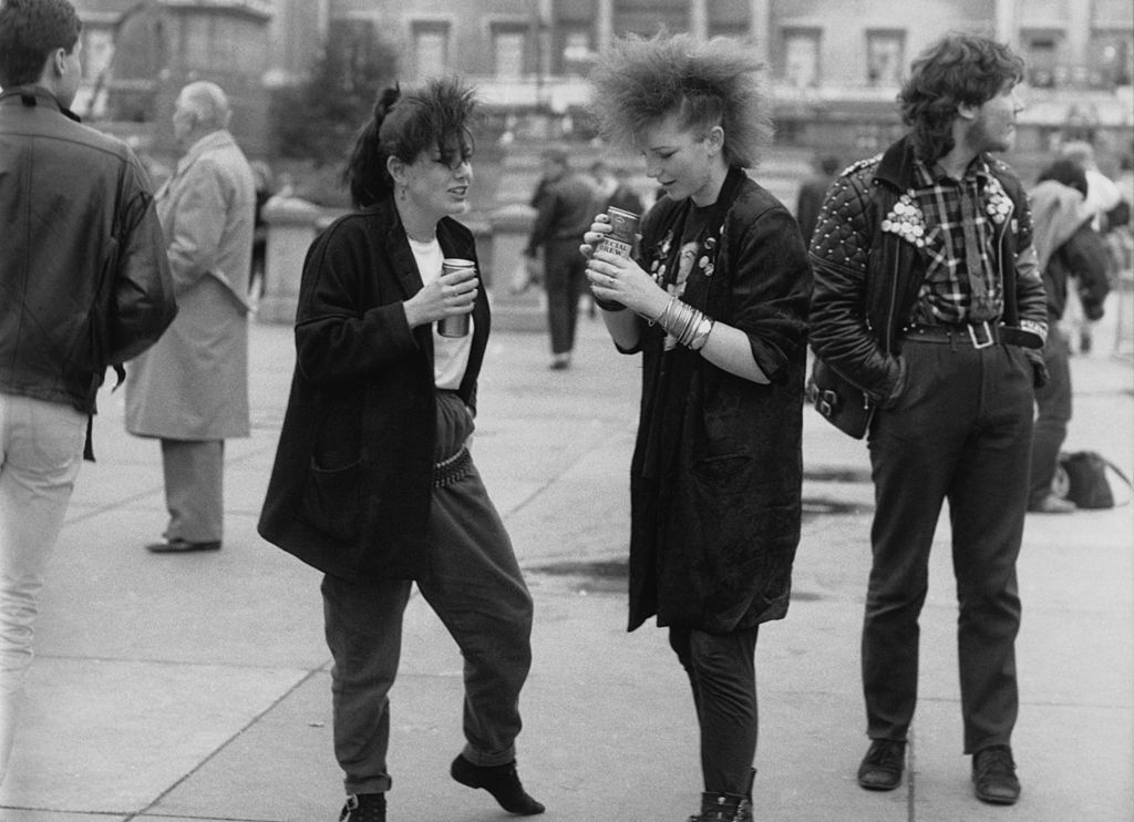 Two young women in post-punk fashions drinking beer from cans