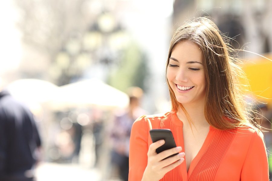 Woman wearing orange shirt texting on smartphone