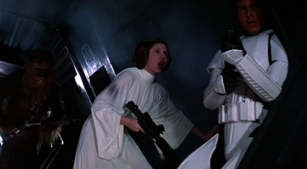 Princess Leia is holding a gun and talking to Han Solo in a hallway in Star Wars: A New Hope