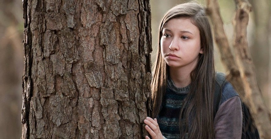 Enid hides behind a tree in a scene from Season 6 of 'The Walking Dead'