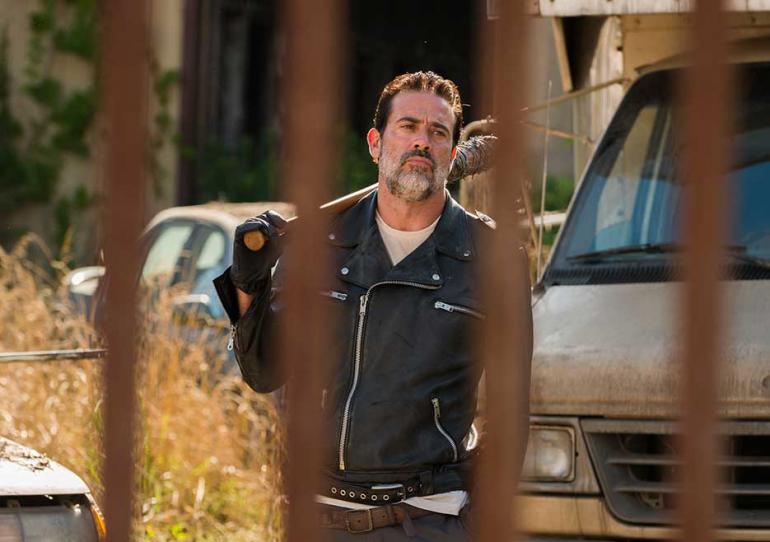 Negan, with Lucille slung over his shoulder, walks toward the Alexandria gates in a scene from 'The Walking Dead' Season 7.