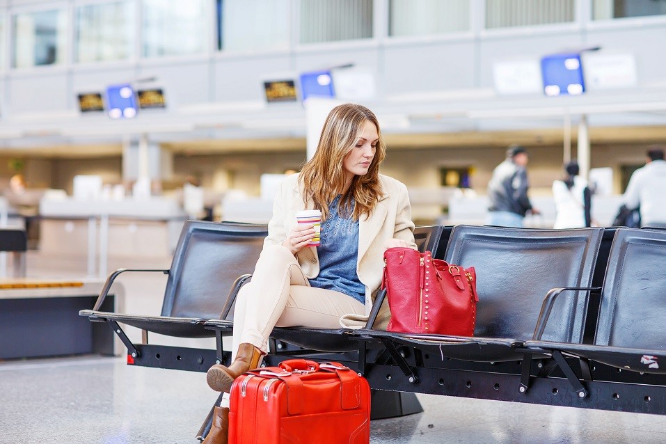 Business woman at international airport sitting and drinking coffee