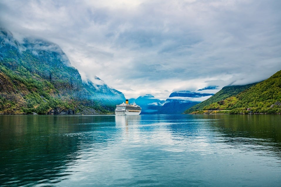 A cruise liner makes its way down a picturesque pathway in Hardangerfjord, Norway