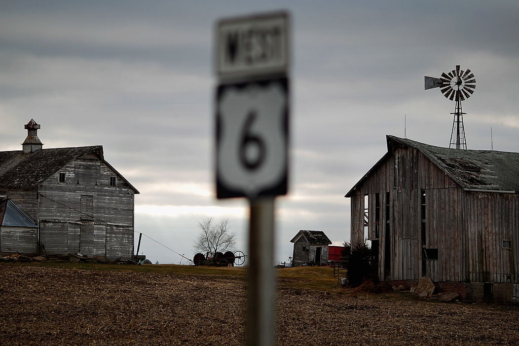 Weather-beaten farm buildings stand along an Iowa highway