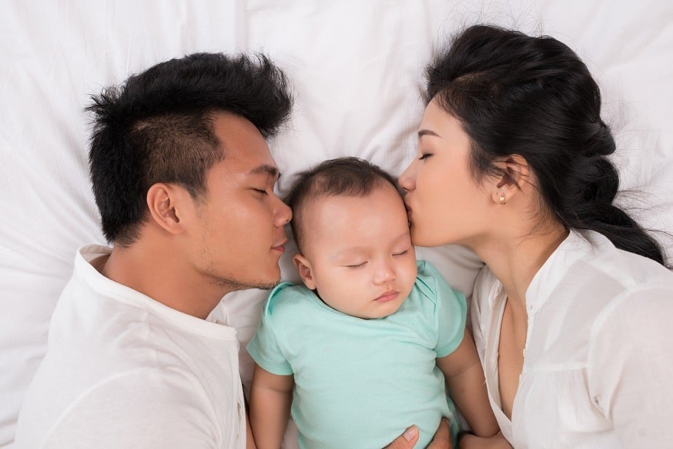 Asian family of three sleeping in bed