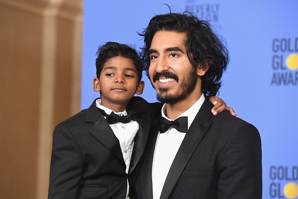 Dev Patel in a tux holding Sunny Pawar