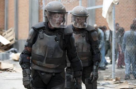 Two walkers wearing riot gear walk in the prison grounds in an episode of 'The Walking Dead'