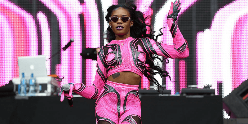 Azealia Banks is dancing in a pink and black outfit on stage.