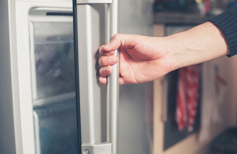 young man is opening a freezer door