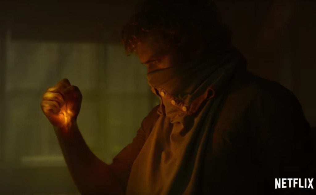 Danny Rand with his fist clenched and glowing yellow, wearing a bandana over his face