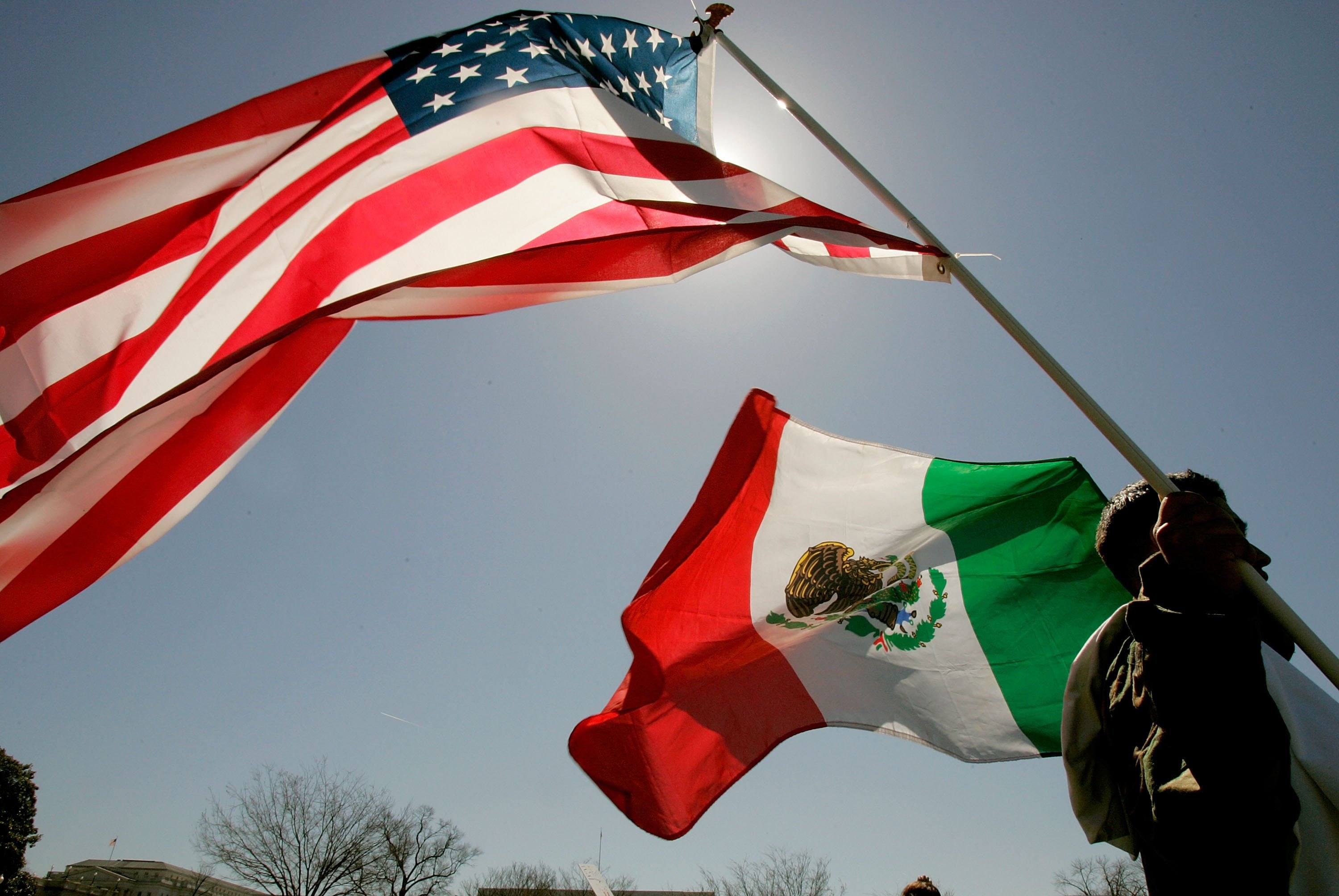A protester holds the flags of both the United States and Mexico
