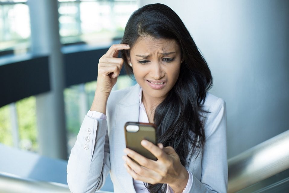 young female worried by what she sees on cell phone