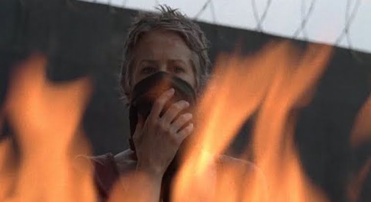 Carol stands and watches flames in a scene from 'The Walking Dead'