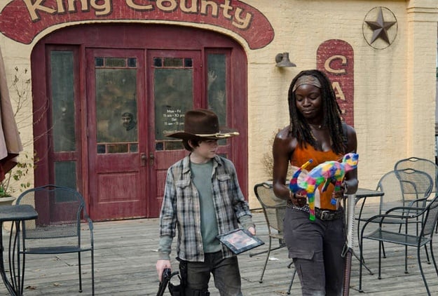 Michonne walking with Carl and holding a rainbow cat statue in 'The Walking Dead' episode 'Clear'