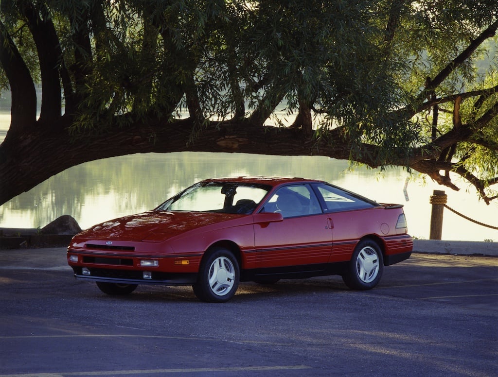 A red 1989 Ford Probe parked under a tree.