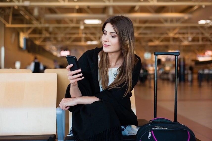 female passenger on smart phone at gate waiting in terminal