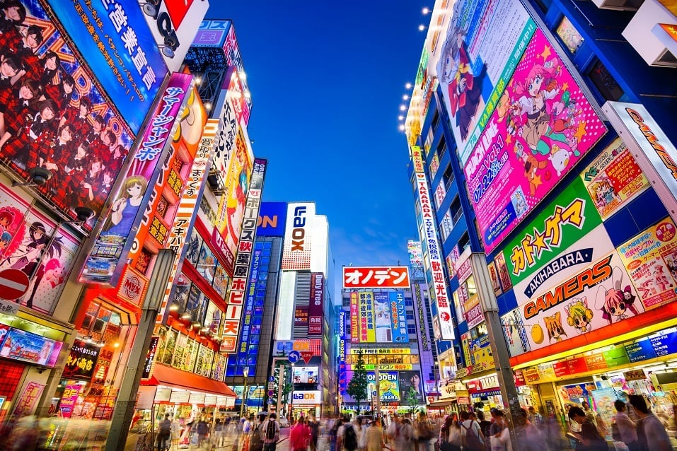 Crowds pass below colorful signs in Akihabara
