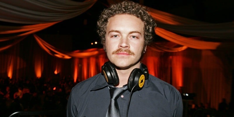 Danny Masterson stares into the camera with headphones around his neck