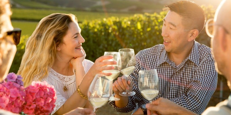 Drew Barrymore and winemaker, Kris Kato drinking wine in a vineyard. 