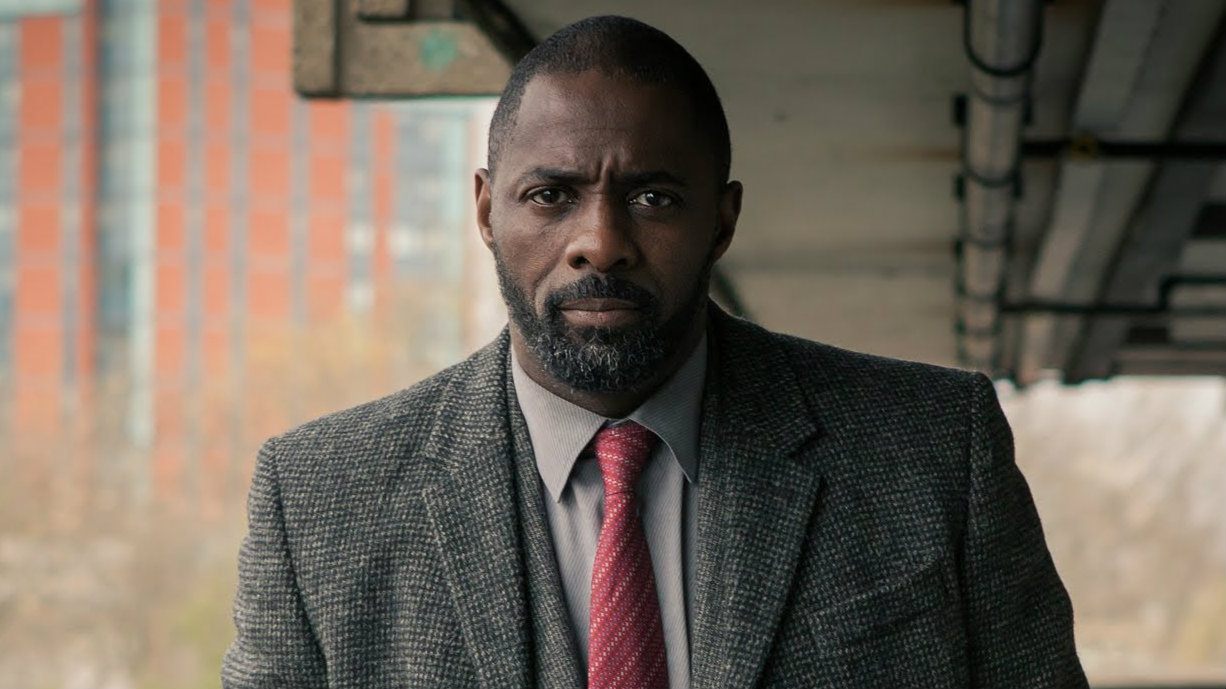 Idris Elba in a suit walking and looking at the camera in Luther