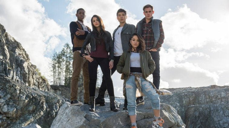 the cast of Power Rangers standing on a rock together