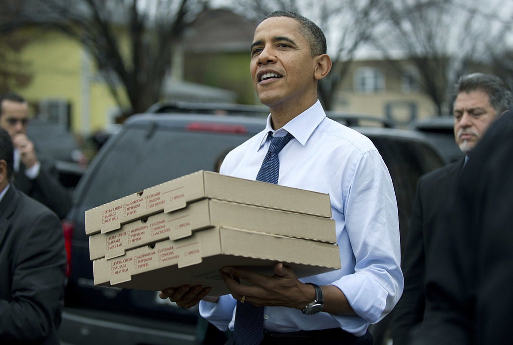 President Barack Obama carries boxes of pizza. 