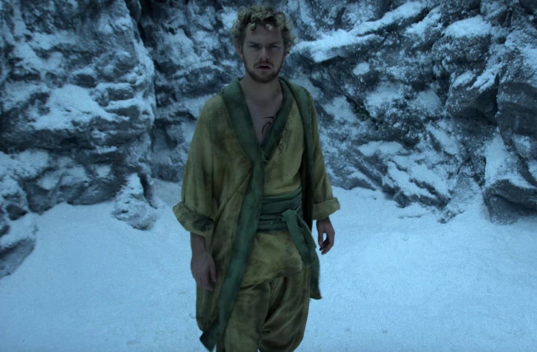 Finn Jones, wearing a yellow robe, and walking through the snow looking dazed