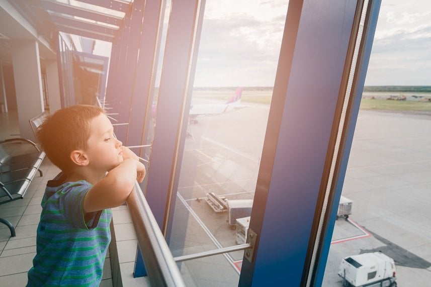 child at the airport, traveling and waiting near window