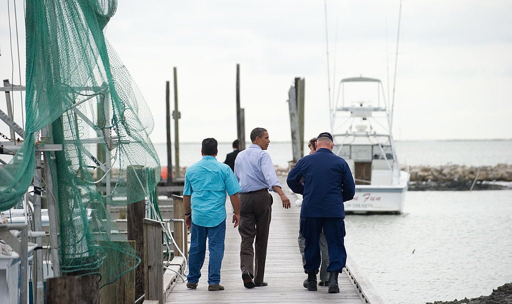 President Barack Obama walks near fishing boats.