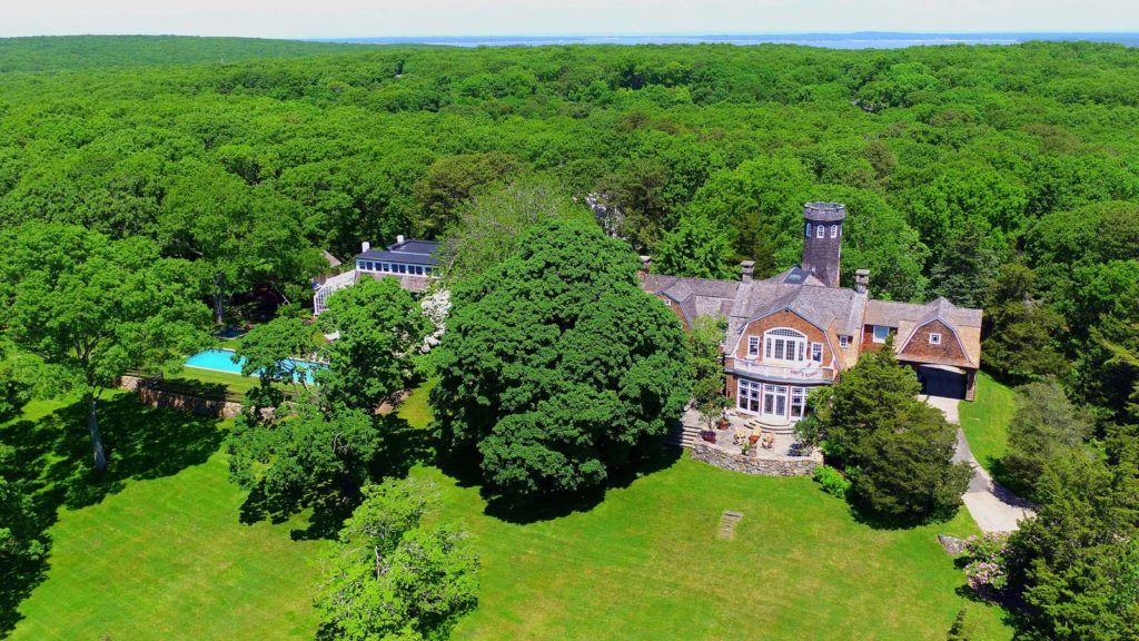 An aerial view of Tower Hill shows the home surrounded by forest and a large yard.