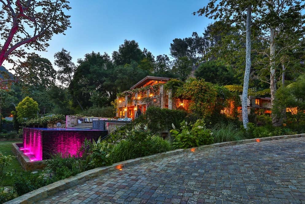 The exterior of Jennifer Lopez's new home features ambient lighting, a large patio and several tall, lush trees.