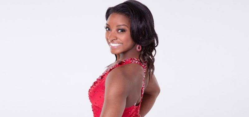 Simone Biles posing in a red dancing outfit for the show