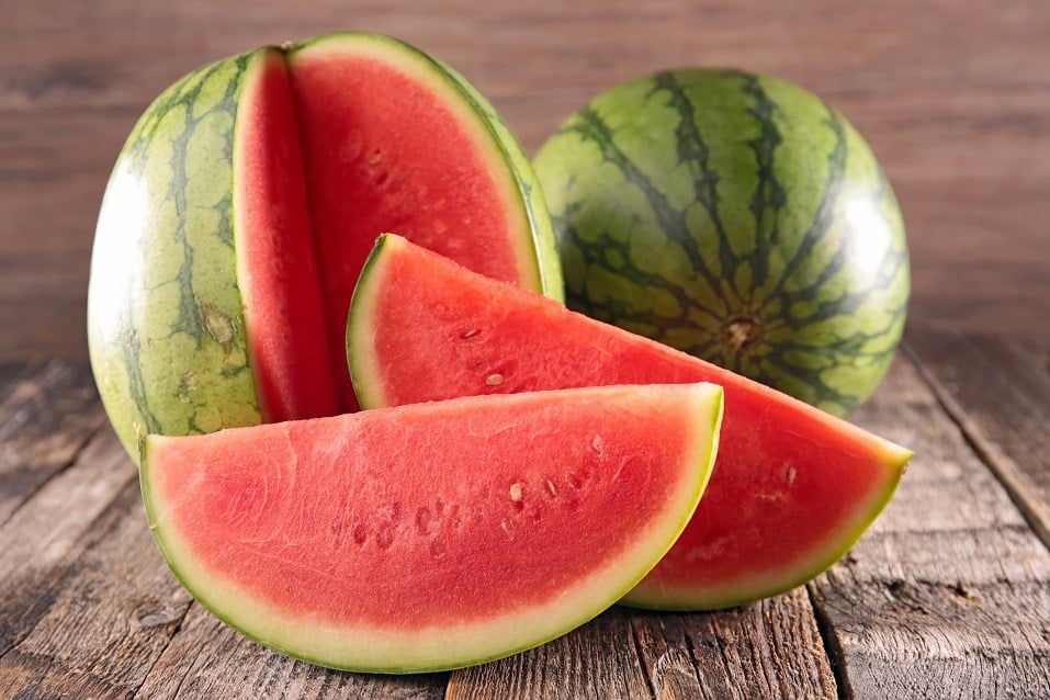 Watermelon sliced into sections and arranged on a wooden table.