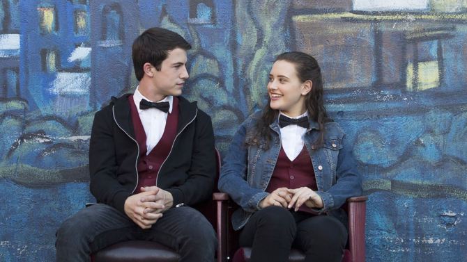 Clay and Hannah wear their movie theater uniforms and sit outside, talking, in a scene from '13 Reasons Why.'