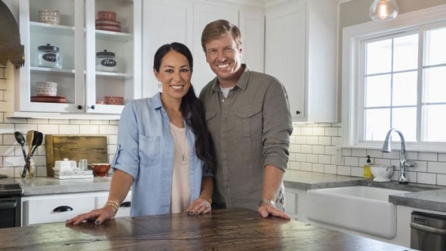 Chip and Joanna Gaines stand at a table in HGTV's Fixer Upper 