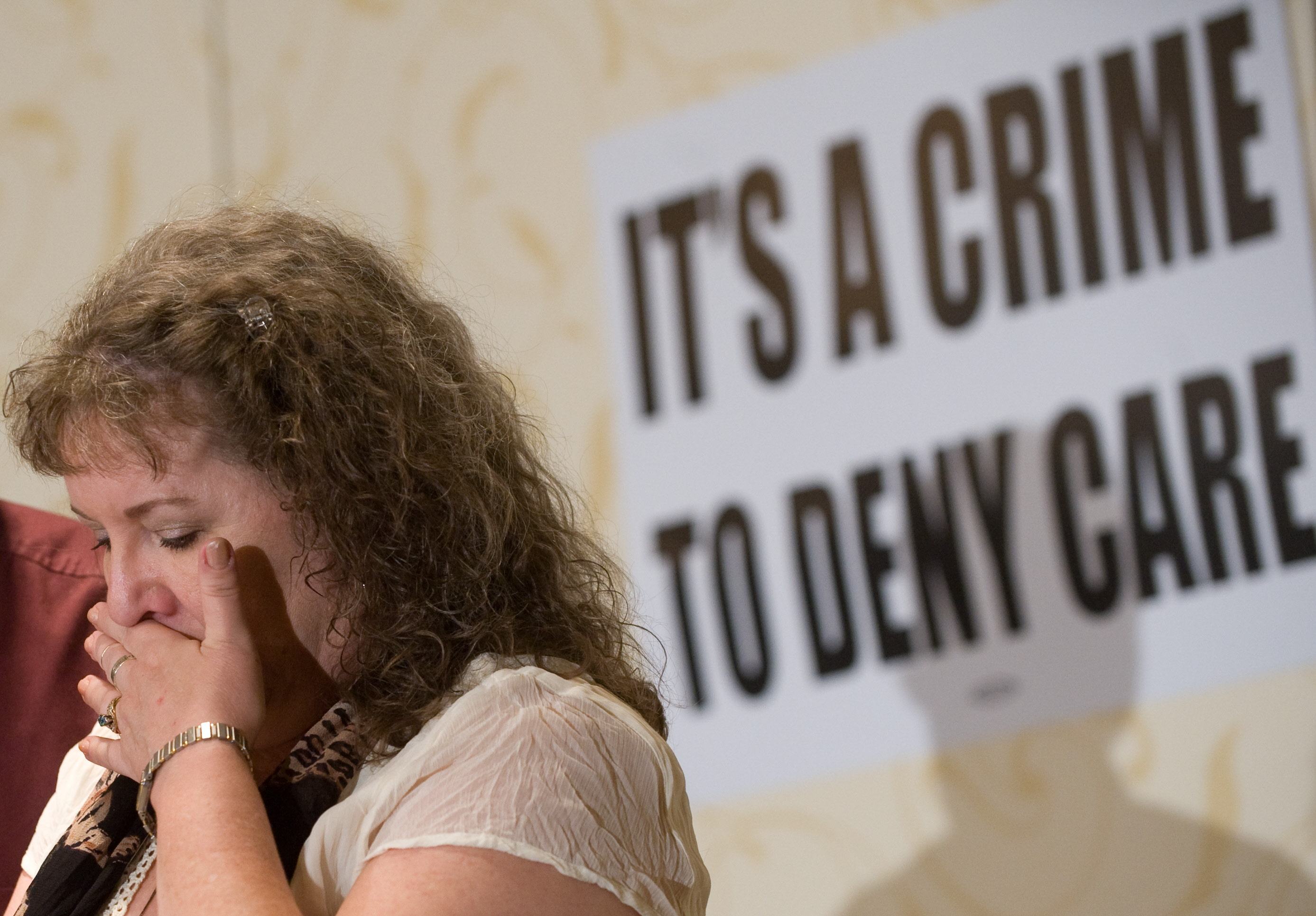 Kelly Arellanes of Little Rock, Arkansas, cries in front of a sign that says "it's a crime to deny care"