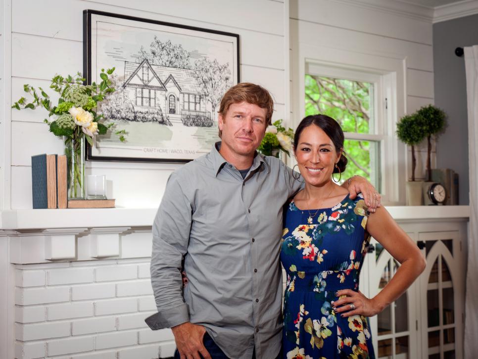 Chip and Joanna Gaines stand in front of a mantle 