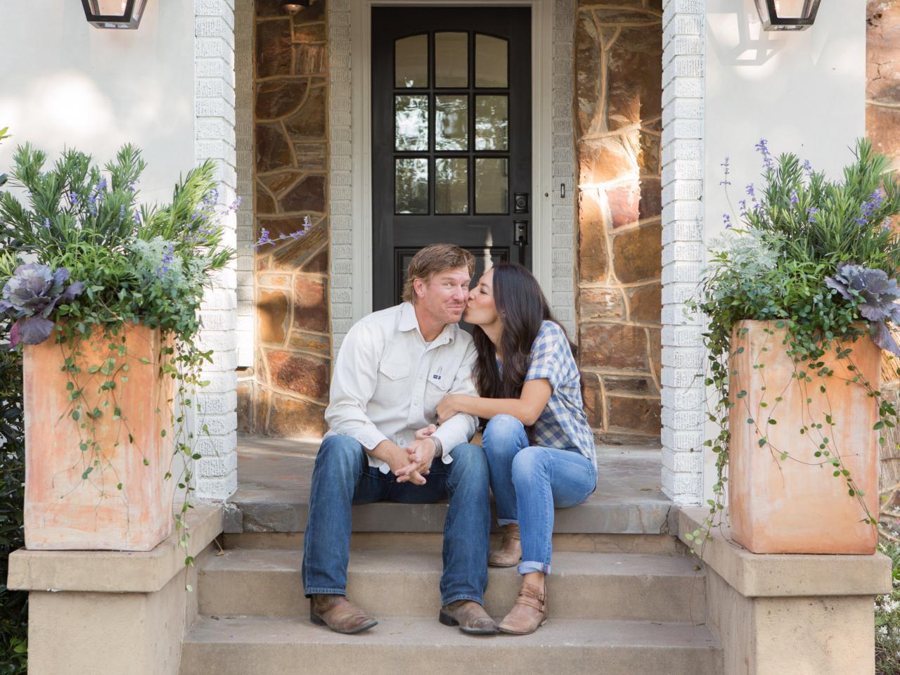 Chip and Joanna Gaines share a kiss while sitting on a stoop in <em>Fixer Upper</em>