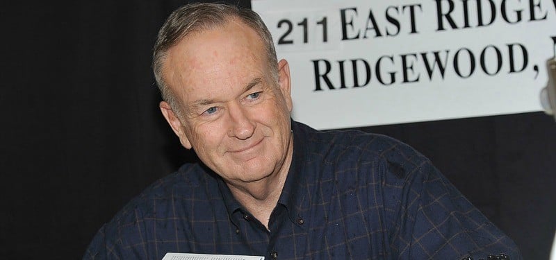 Bill O' Reilly is smiling while he is signing books.