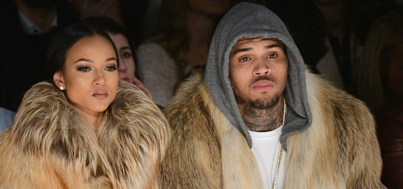 Karreuche Tran and Chris Brown are sitting down front row at a fashion show in fur coats.