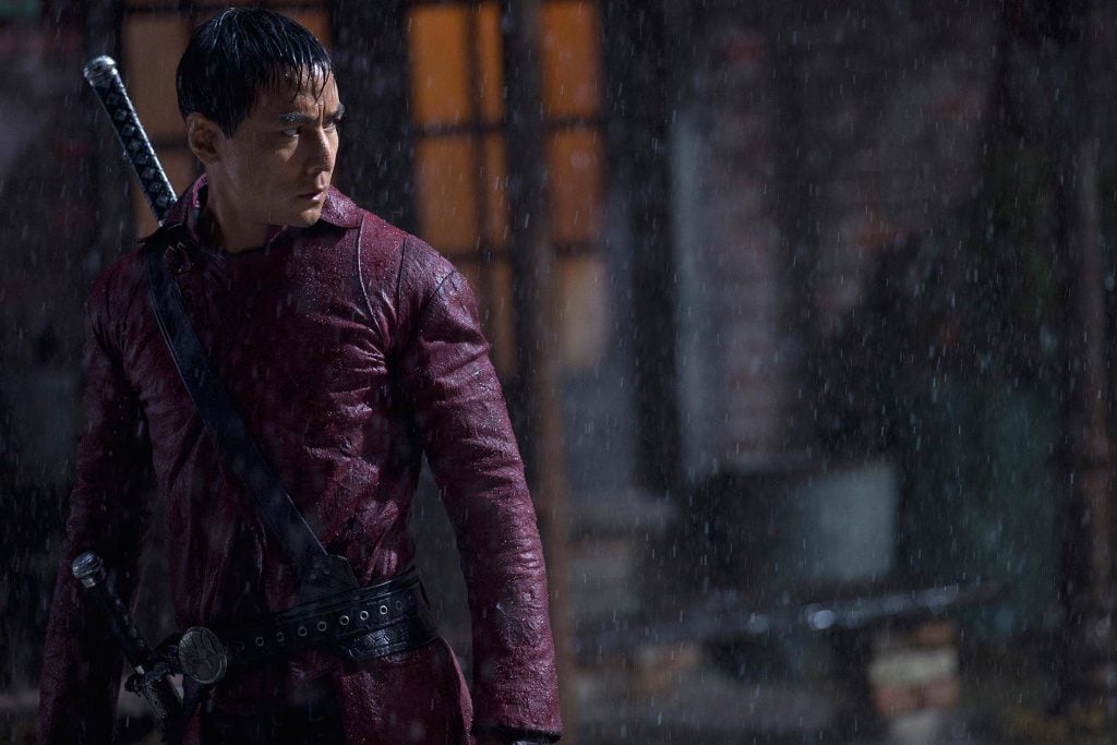 Daneil Wu in a red leather jacket, with a sword strapped across his back