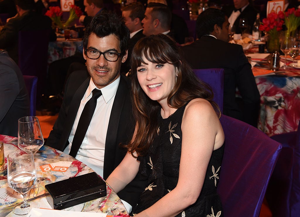 Jacob Pechenik and Zooey Deschanel smiling together, sitting at a table