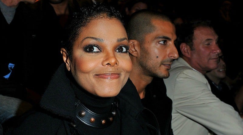 Janet Jackson gives a tight smile to the camera as she sits next to Wissam Al Mana at a fashion show.