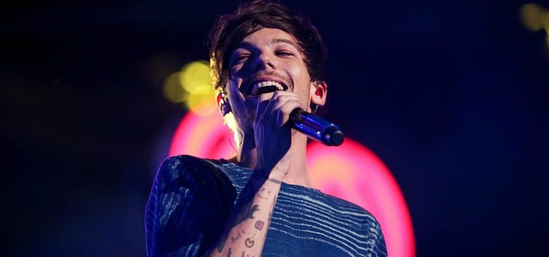 Louis Tomlinson is singing on stage.