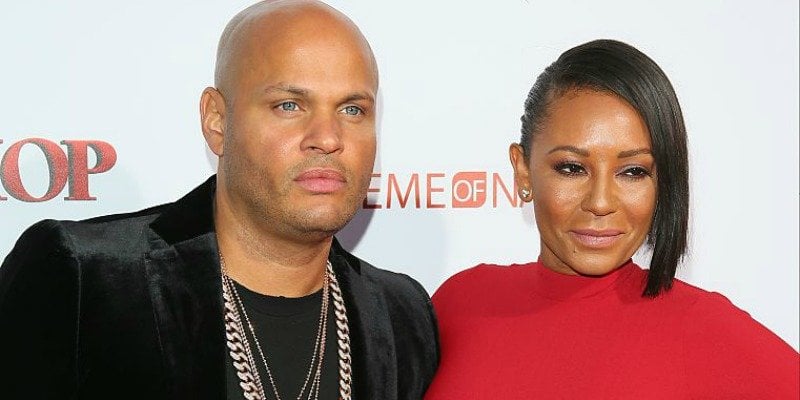 Mel B is in a red dress with Stephen Belafonte who is in a black outfit on the red carpet.